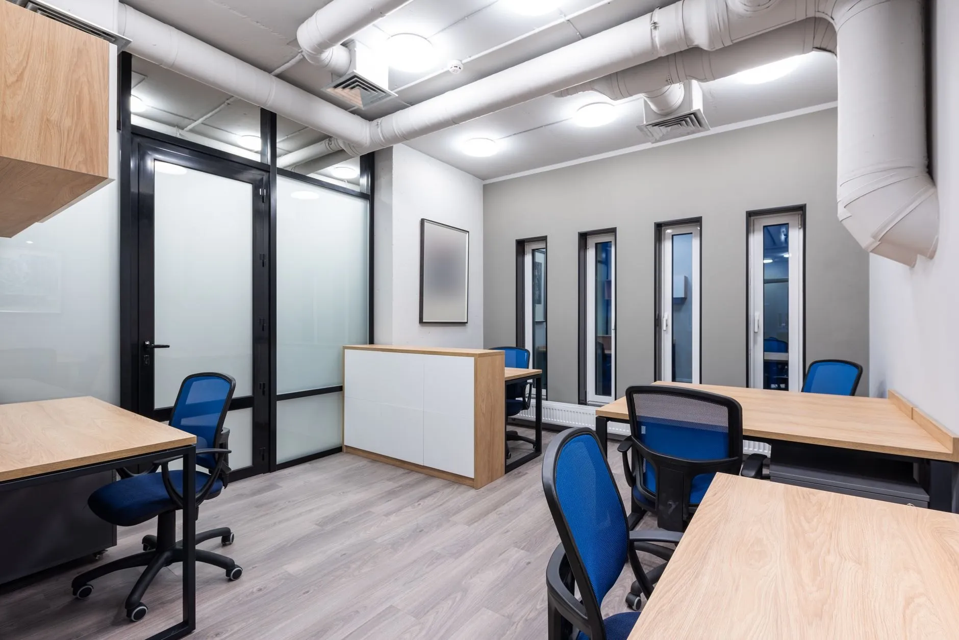 A clean, empty office with light wood desks and blue chairs
