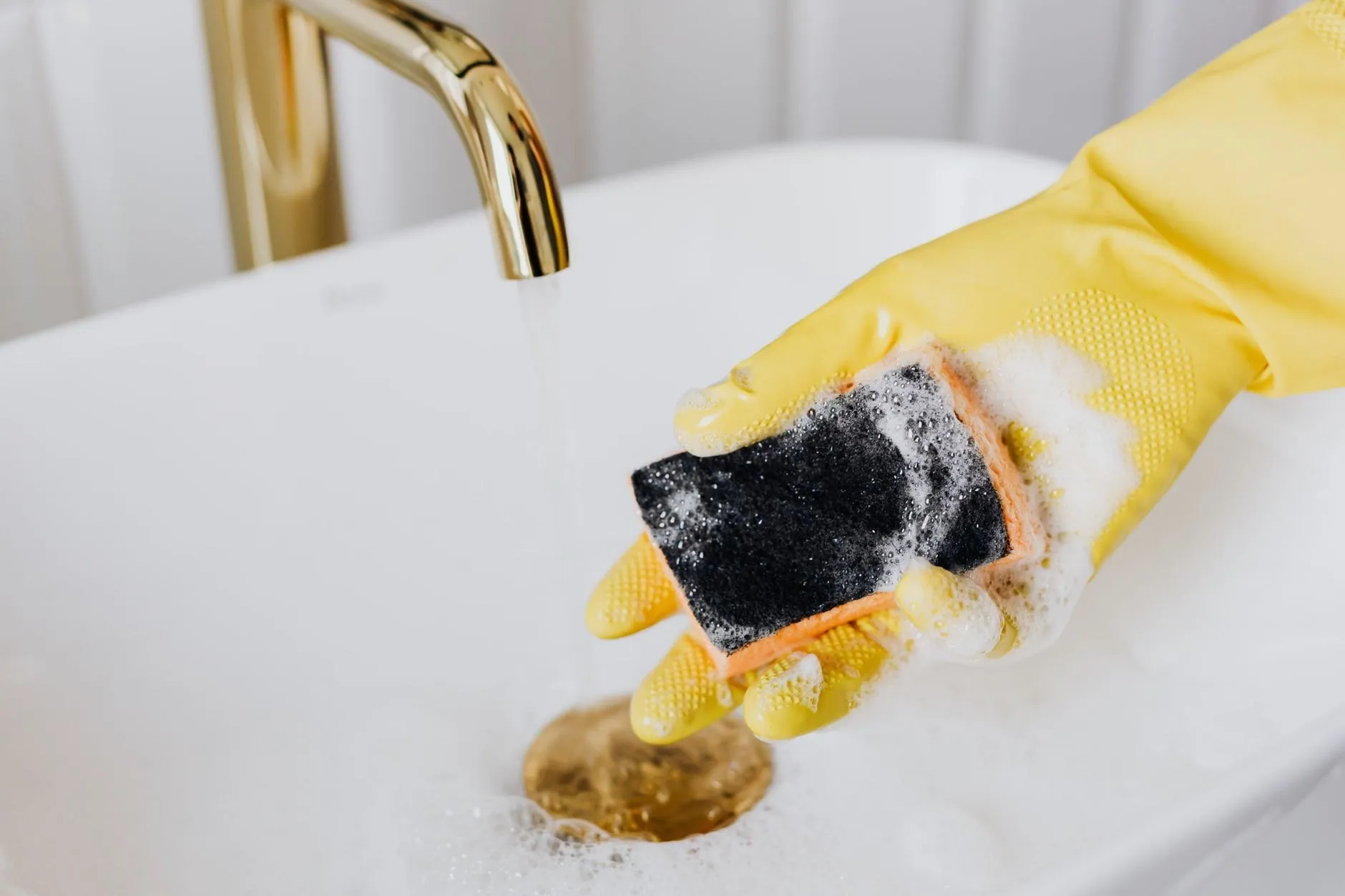 A basin with a stained plughole and soap scum before cleaning